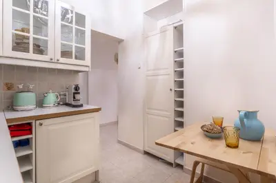 a kitchen with white cabinets and a wooden table at iFlat Comfy apt a few steps from the Vatican in Rome