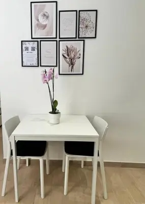 a white table and chairs with pictures on the wall at Little Apartment in Rome
