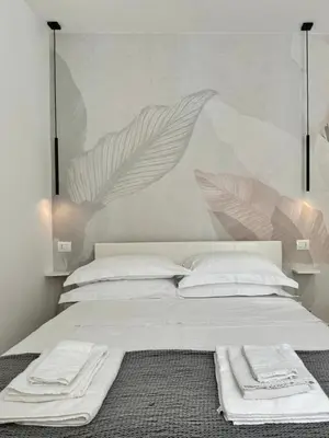 a white bed with white pillows and a mural at Little Apartment in Rome