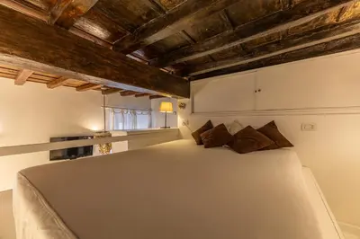 a bedroom with a large white bed with wooden ceilings at Piazza Navona Elite Flat in Rome