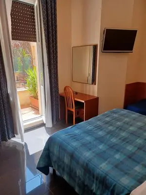 a bedroom with a bed and a desk and a window at PITAGORA Rooms in Rome