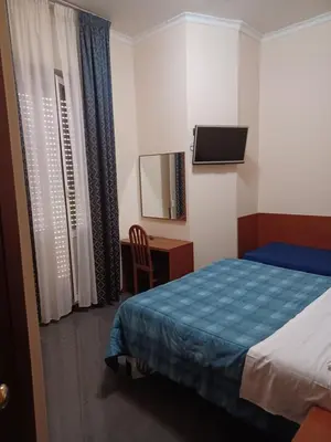 a bedroom with a bed and a desk and a television at PITAGORA Rooms in Rome