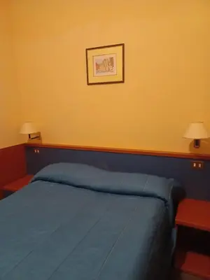a bedroom with a blue bed and a yellow wall at PITAGORA Rooms in Rome