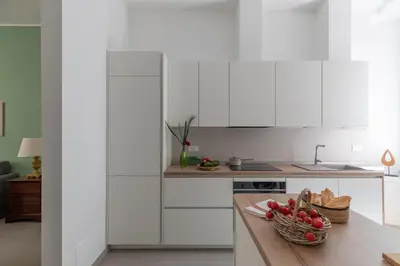 a kitchen with white cabinets and a bowl of fruit on a counter at iFlat Soft & Relaxing apt in Trastevere in Rome