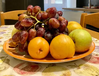 a plate of grapes and apples on a table at Brandnew luxury house near metro station in Rome