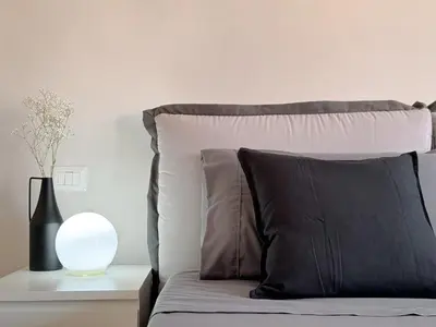 a bed with a black pillow and a white lamp at Lumen House - Attico con Suite in Rome