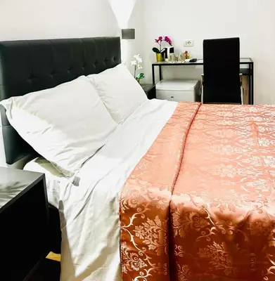 a bedroom with a bed with an orange and white comforter at Rome Holiday Guesthouse in Rome
