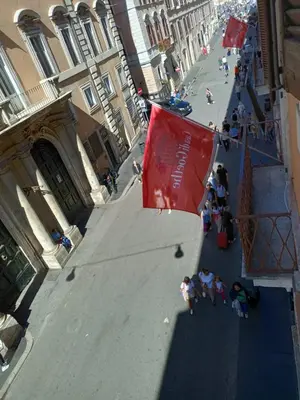 a group of people walking down a street with a red flag at Rooms house corso 22 in Rome