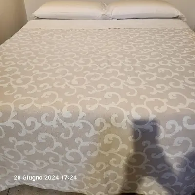 a bed with a white comforter on top of it at Rooms house corso 22 in Rome