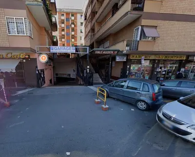 a parking lot with cars parked in front of a building at City Vibe Red Rose in Rome