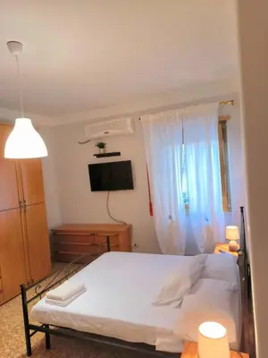 a bedroom with a white bed and a television at Bilocale in Via degli Orti Variani in Rome
