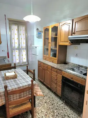 a kitchen with wooden cabinets and a table in it at Bilocale in Via degli Orti Variani in Rome