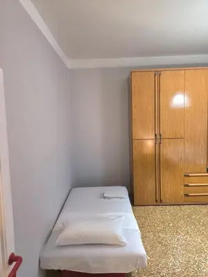 a small bedroom with a bed and a wooden cabinet at Bilocale in Via degli Orti Variani in Rome
