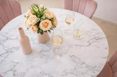 a white marble table with wine glasses and a vase with flowers at Colosseum window 1800-Romantic apartment Rome in Rome