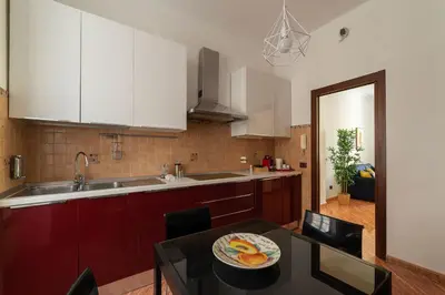 a kitchen with white cabinets and a table with a plate of fruit at CS Beautiful San Giovanni Apt in Rome