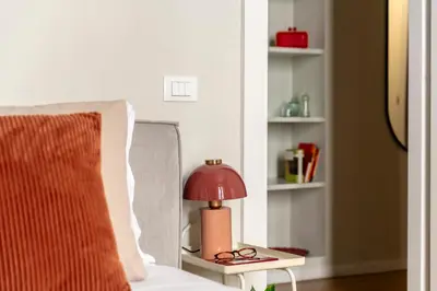 a red lamp sitting on a table next to a bed at Casa Gracchi by Hili in Rome