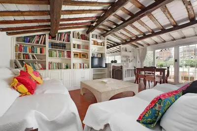 a living room with two beds and a book shelf at Magical Navona Duplex With Terrace by Halldis in Rome