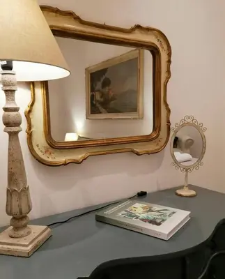 a lamp on a table with a mirror and a book at Borgo Pio 51 Apartment Vatican in Rome