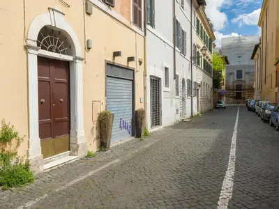 a cobblestone street with buildings and a brown door at Sales in Trastevere in Rome