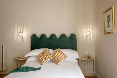 a bedroom with a bed with a green headboard and pillows at Daplace - Lucilla Apartment in Rome