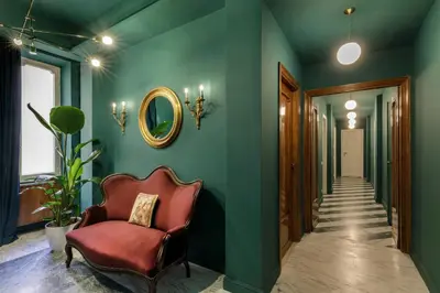 a hallway with green walls and a red chair at Daplace - Lucilla Apartment in Rome