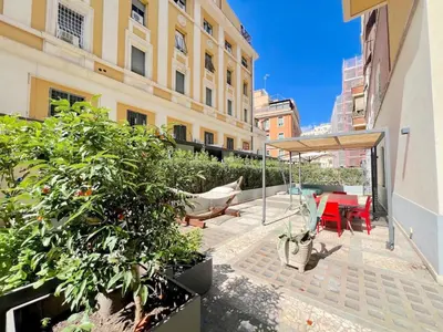 a patio with a red table and chairs in a building at The Garden in Parioli in Rome