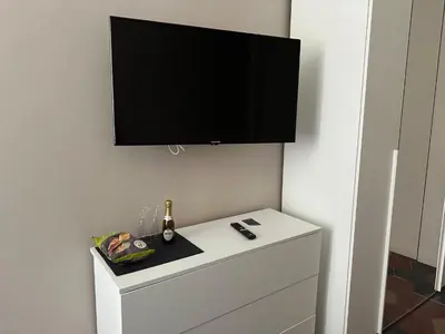 a flat screen tv on a wall with a white dresser at Vaticano Roma Guesthouse in Rome