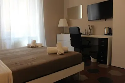 a bedroom with a bed with a desk and a television at Vaticano Roma Guesthouse in Rome