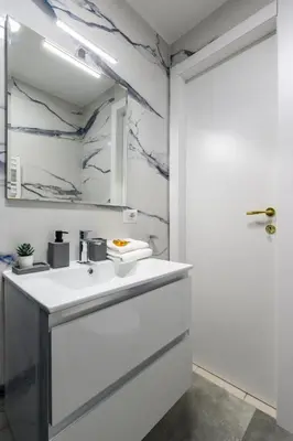 a white bathroom with a sink and a mirror at HB Montebello apartment in Rome