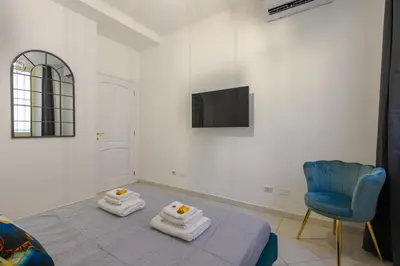 a white room with a bed and a blue chair at HB Montebello apartment in Rome