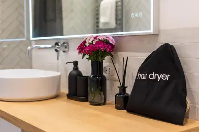 a bathroom counter with a sink and flowers and a bag at Trevi Fountain Boutique Apartment in Rome