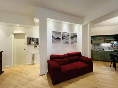 a living room with a red couch and a kitchen at Appartamento con giardino tra San Pietro e Stadio Olimpico Roma in Rome
