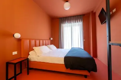 a bedroom with orange walls and a bed with a window at Luciano Queen's Guest House in Rome
