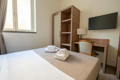 a bedroom with a bed and a desk and a television at Casa per Ferie Santa Maria alle Fornaci in Rome