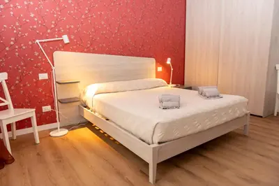 a bedroom with a bed and a red wall at Casa Caterina Holiday House - Bright Modern Apartment Near Trastevere in Rome