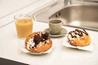 two donuts sitting on a counter next to a glass of orange juice at Domina Apartments Roma - San Pietro 2 in Rome