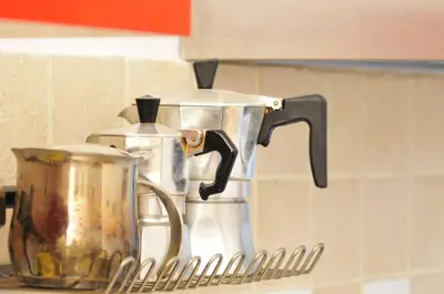two coffee pots and pans on a drying rack at CARDINAL STUDIO - 2 steps from Vatican & Ottaviano metro in Rome