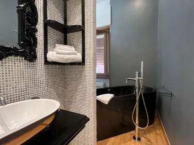 a bathroom with a black tub and a sink at Alileo At The Vatican in Rome