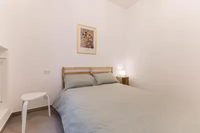 a white bedroom with a bed and a stool at Al 32C del Gianicolo in Rome
