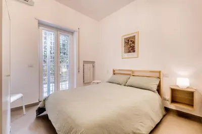 a white bedroom with a large bed and a window at Al 32C del Gianicolo in Rome