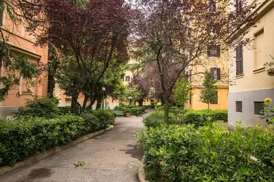 a walkway between two buildings with trees and bushes at Esa apartment Flaminio in Rome