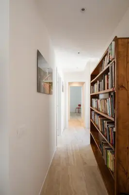a hallway with bookshelves and a wall filled with books at Suite Lucrezio in Rome in Rome