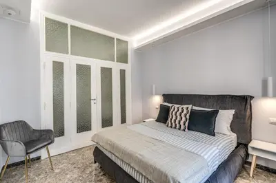a white bedroom with a bed and a chair at 3Storie Vatican St Peter in Rome