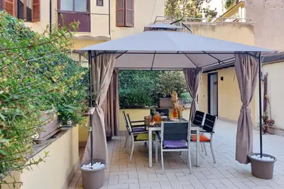 a table and chairs under an umbrella on a patio at dolce casa colosseo 1 - 2 in Rome