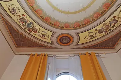 an ornate coffered ceiling with yellow curtains and a window at dolce casa colosseo 1 - 2 in Rome