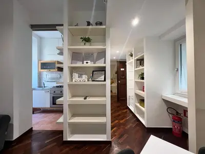 a living room with white shelves and a kitchen at Suite Vaticana 9 in Rome