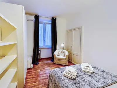 a bedroom with a bed and a chair and a window at Suite Vaticana 9 in Rome