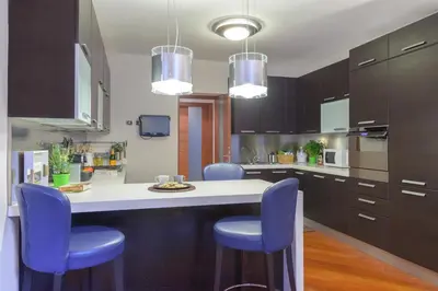 a kitchen with a white counter and blue chairs at Rome Guest House Saint Peter in Rome