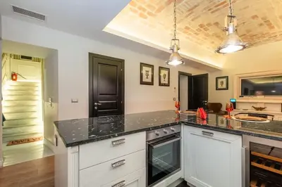 a kitchen with white cabinets and a black counter top at La Casa dei Sogni Roma in Rome