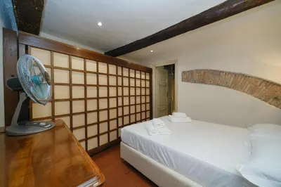 a bedroom with a white bed and a fan at Pantheon's Arch by BuddyRent in Rome